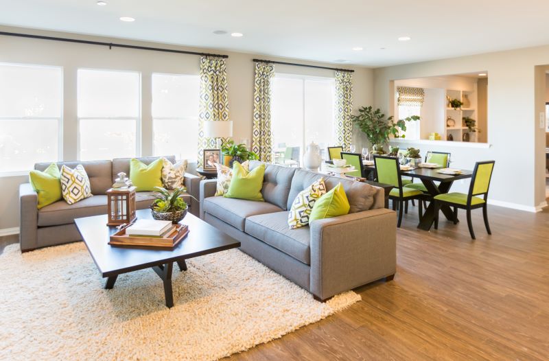 Sala de estar conjugada com sala de jantar, onde o verde limão predomina nas cadeiras, almofadas e nas estampas das cortinas.